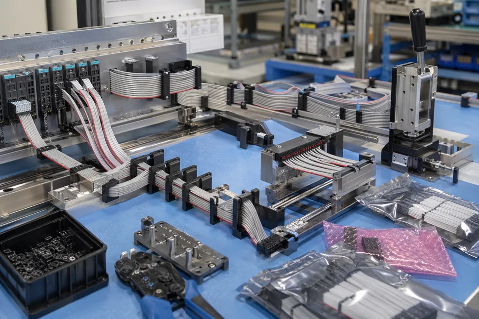 Industrial-control IDC production workstation with PLC module fixtures and routed ribbon harnesses